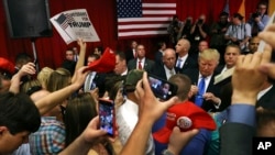 Supporters wave signs as Republican presidential candidate Donald Trump, center right, signs autographs for supporters after speaking at a campaign event Thursday, May 19, 2016, in Lawrenceville, N.J