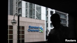 A man walks on a footbridge connected to Standard Chartered headquarters in Hong Kong, August 7, 2012.