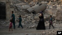 FILE - Iraqi civilians are seen walking past the destroyed al-Nuri mosque in the Old City of Mosul, Iraq, July 4, 2017.