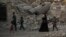 FILE - Iraqi civilians are seen walking past the destroyed al-Nuri mosque in the Old City of Mosul, Iraq, July 4, 2017.