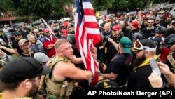 Joseph Oakman dan rekan-rekannya dari Proud Boys, memasang benderad di Taman Tom McCall di dalam pawai "anti teroris domestik" di Portland, Oregon, Sabtu, 17 Agustus 2019.