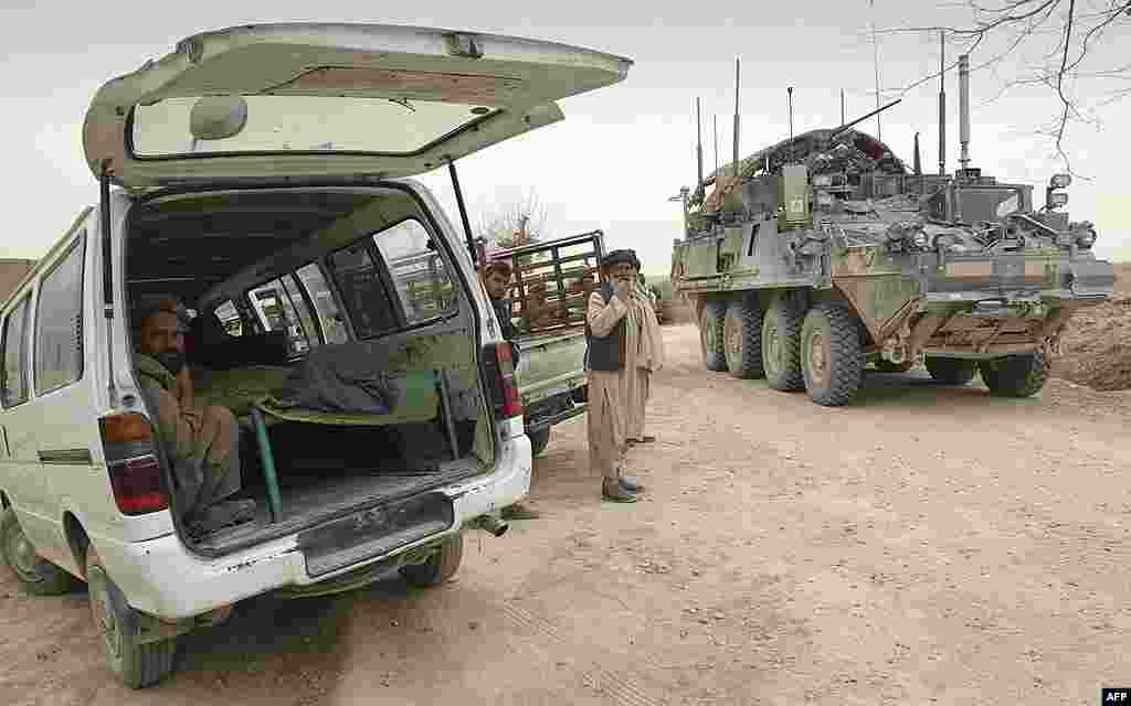 An armored military vehicle from the NATO-led International Security Assistance Force (ISAF) is seen at right, as the covered body of a person who was allegedly killed by a U.S. service member is seen inside a minibus in Panjwai. (AP) 