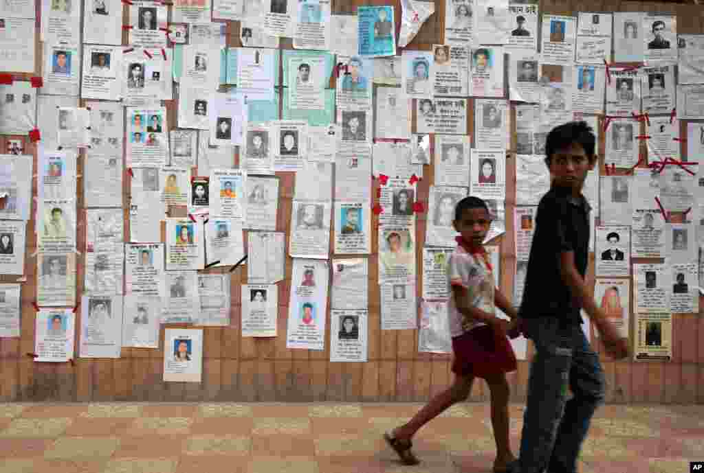 Two youths walk past a wall pasted with flyers showing some of the missing on Monday April 29, 2013 in Savar, near Dhaka, Bangladesh.