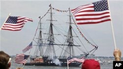 Spectators wave flags as the USS Constitution fires its cannons off Castle Island in Boston, Massachussetts, on its annual 4th of July turn-around in Boston Harbor, July 4, 2011