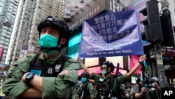 Seorang polisi memegang spanduk peringatan untuk para demonstran pada Hari Nasional China di Causeway Bay, Hong Kong, Kamis, 1 Oktober 2020. (AP Photo/Vincent Yu)