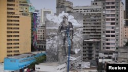 Brazilian artist and activist Mundano works on the mural 'The Forest Brigade' using paint made with ashes collected and brought from fires in Amazon, Pantanal and other biomes, in Sao Paulo, Brazil October 14, 2021. (REUTERS/Amanda Perobelli)