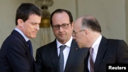 French President Francois Hollande (C) speaks with Interior minister Bernard Cazeneuve (R) and Prime Minister Manuel Valls at the end of the weekly cabinet meeting at the Elysee Palace in Paris, April 22, 2015. 