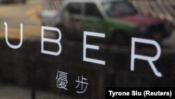 Un taxi se reflète sur une fenêtre des bureaux de Uber à Hong Kong en Chine le 12 août 2015.