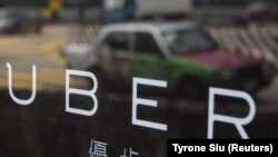 Pantulan sebuah taksi di jendela kantor Uber Inc di Hongkong, China (12/8/2015). (foto: REUTERS/Tyrone Siu)