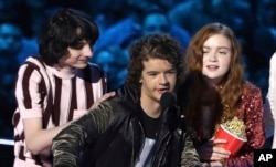 In this Saturday, June 16, 2018, photo, Finn Wolfhard, from left, Gaten Matarazzo and Sadie Sink accept the award for best show for "Stranger Things" at the MTV Movie and TV Awards at the Barker Hangar in Santa Monica, Calif.