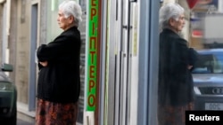 A woman waits for the opening of a branch of Laiki Bank in Nicosia, March 29, 2013.