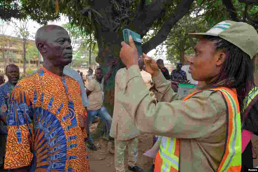 A member of the National Youth Service Corps (NYSC) takes a photograph of a voter using Bimodal Voter Accreditation System (BVAS) during Nigeria&#39;s Presidential election, in Lagos, Nigeria February 25, 2023.