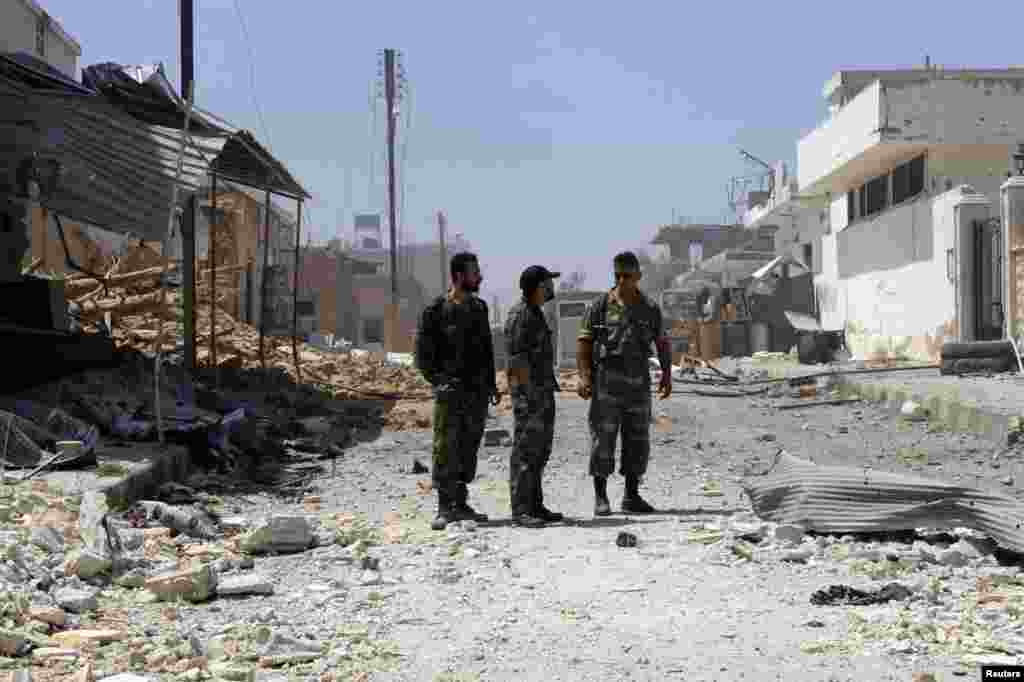 Soldiers loyal to Syrian President Bashar al-Assad stand on a damaged street full of debris in Qusair, June 6, 2013. 
