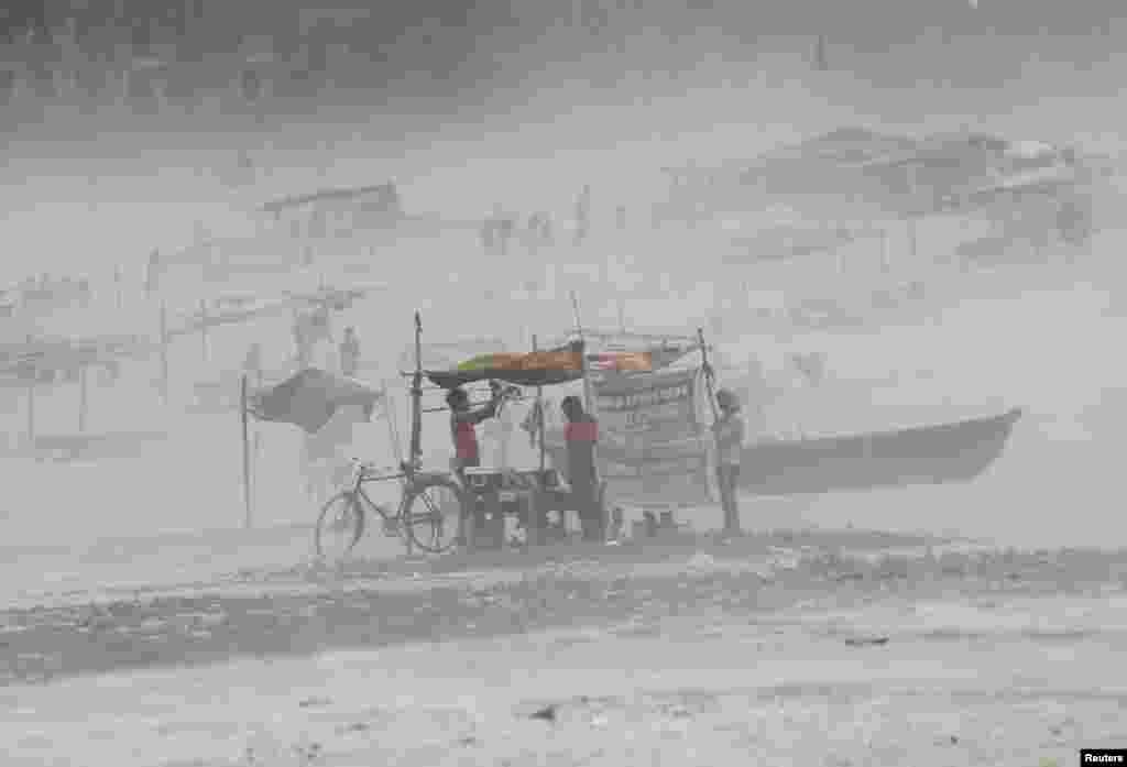 A man fixes a tarpaulin on his stall during a dust storm on the banks of the river Ganges in the northern Indian city of Allahabad.