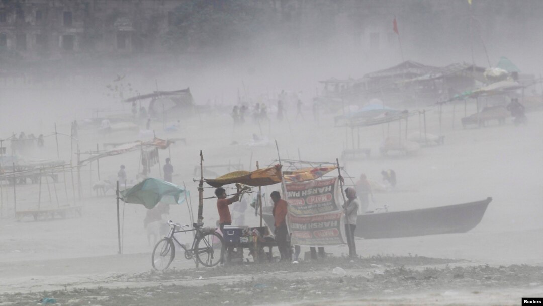 Seorag pria membetulkan terpal di warungnya saat badai menghantam sekitar wilayah Sungai Gangga di Allahabad (13/10).