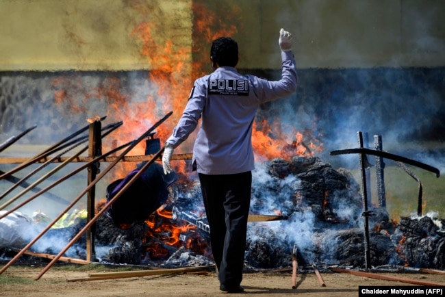 Seorang polisi membakar setumpuk ganja sitaan saat upacara di Mapolres Banda Aceh pada 23 September 2020. (Foto: AFP/Chaideer Mahyuddin)