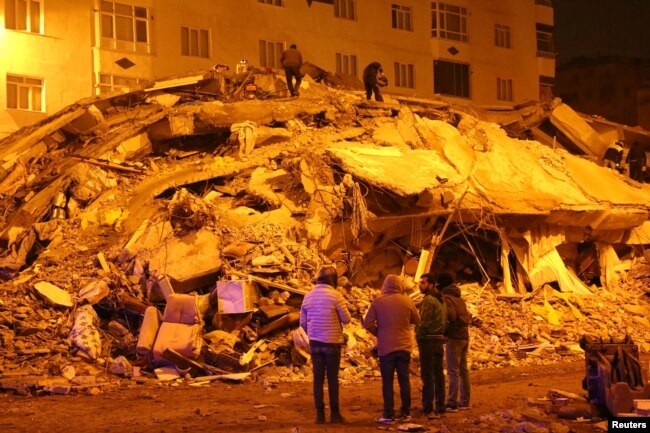 Orang-orang melihat bangunan yang runtuh setelah gempa bumi di Diyarbakir, Turki 7 Februari 2023. (Foto: REUTERS/Sertac Kayar)