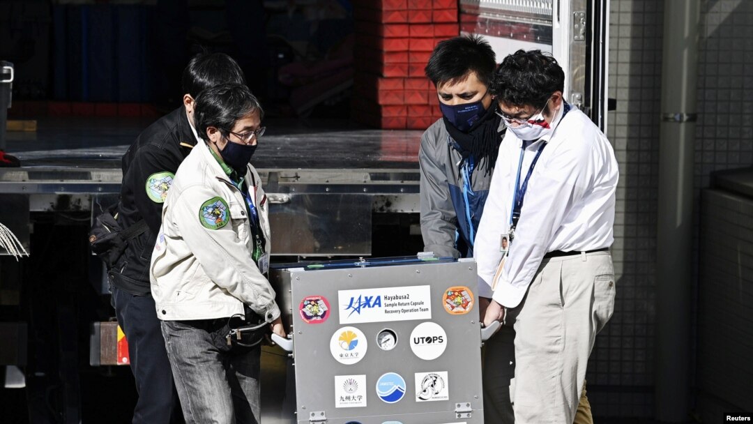 Japan Aerospace Exploration Agency's (JAXA) staff carry a case containing Hayabusa2's capsule with extensive samples of an asteroid as it arrives at JAXA Sagamihara Campus in Sagamihara in this photo taken by Kyodo, Dec. 8, 2020. 