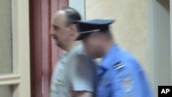 Goran Hadzic (L), a Croatian Serb wartime leader indicted for crimes against humanity during the 1991-95 Croatian war, enters a special court escorted by a policeman in this handout photo taken in Belgrade, July 20, 2011.