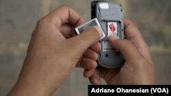 FILE - A mobile phone user in Juba, South Sudan, removes his smartphone battery.