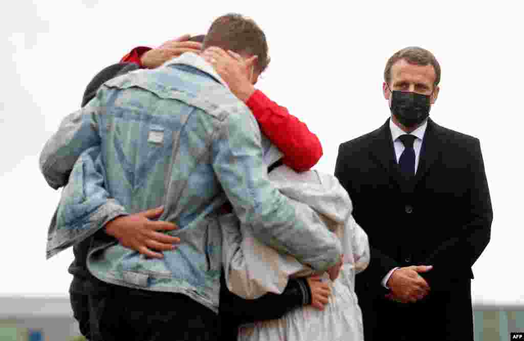 French President Emmanuel Macron stands by as French aid worker Sophie Petronin, center, is welcomed by her family after suspected jihadist hostage-takers freed the 75-year-old from nearly four years of captivity in Mali, upon her arrival near Paris. 