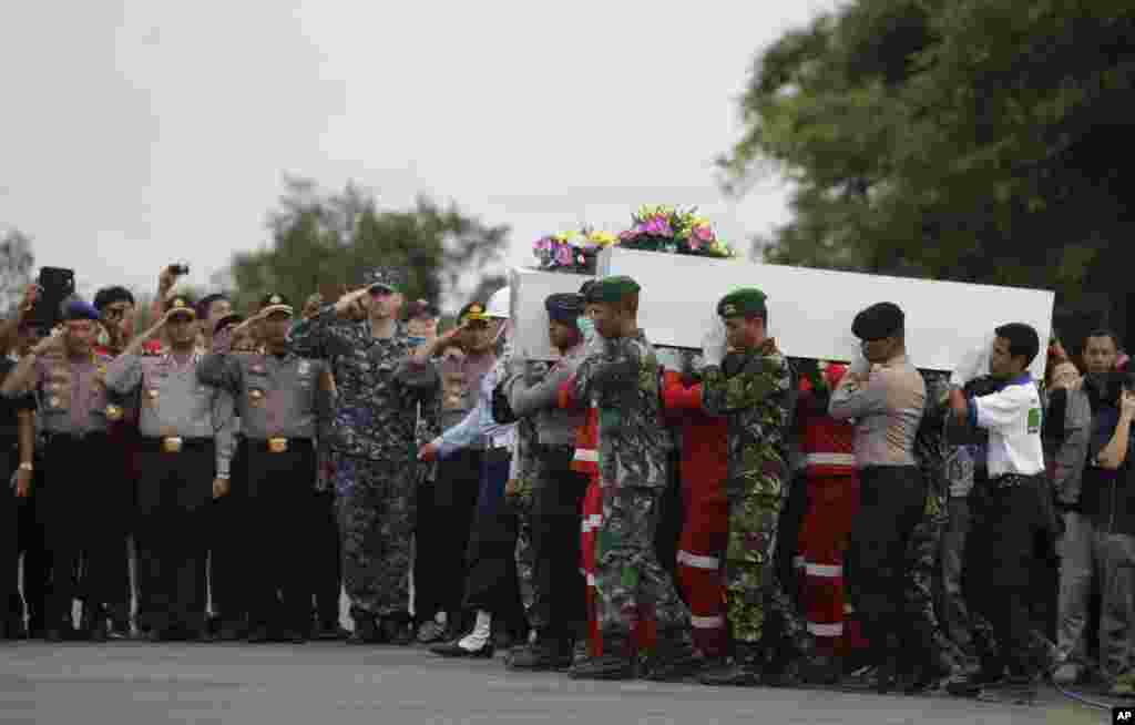 Anggota Tim SAR nasional dan tentara Indonesia mengangkat peti jenazah korban AirAsia 8501 ke Surabayadi bandara Pangkalan Bun, Indonesia (2/1).