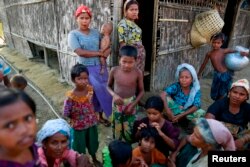 FILE - Rohingya Muslims pass time near their shelter at a refugee camp outside Sittwe, Myanmar, June 4, 2014.