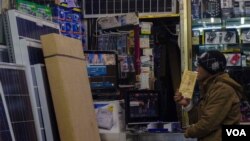 A customer looks over solar power panels in a retail outlet in Yemen's capital, Sanaa. Photo: VOA / C. Coombs