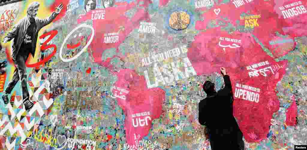 A man signs his autograph on the legendary graffiti-covered John Lennon Wall after it was repainted to mark the 30th anniversary of the fall of the communism in Prague, Czech Republic.