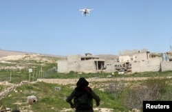 FILE - A female Kurdistan Workers Party (PKK) fighter waits for a drone to land, in Sinjar, March 11, 2015. The drone had flown to check enemy positions near a site which had been hit by two Islamic State car bombs.