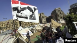 Anti-Mursi protesters sit outside their tents, below a flag that reads, "No, to Constitution" at Tahrir Square in Cairo December 10, 2012. The Egyptian government has given the military the authority to arrest civilians to help safeguard a constitutional 