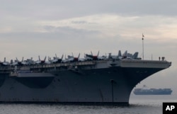 Sailors and fighter jets are seen on the deck of the U.S. aircraft carrier USS Ronald Reagan (CVN 76) as it anchors off Manila Bay for a goodwill visit, June 26, 2018, west of Manila, Philippines.