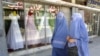 FILE - Afghan women walk past a shop specialising in wedding dresses in Kabul.
