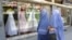 FILE - Afghan women walk past a shop specialising in wedding dresses in Kabul.