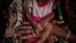 Abeba Gebru, 37, from the village of Getskimilesley, holds the hands of her malnourished daughter, Tigsti Mahderekal, 20 days old, in the treatment tent of a medical clinic in the town of Abi Adi, in the Tigray region of northern Ethiopia, on…