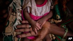 FILE - Abeba Gebru, 37, holds the hands of her malnourished daughter, Tigsti Mahderekal, 20 days old, in a medical clinic in the town of Abi Adi, in the Tigray region of northern Ethiopia, on May 11, 2021.
