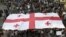 Georgian demonstrators carry a state flag during a protest rally against prison abuse in Tbilisi, Georgia, Sept. 20, 2012