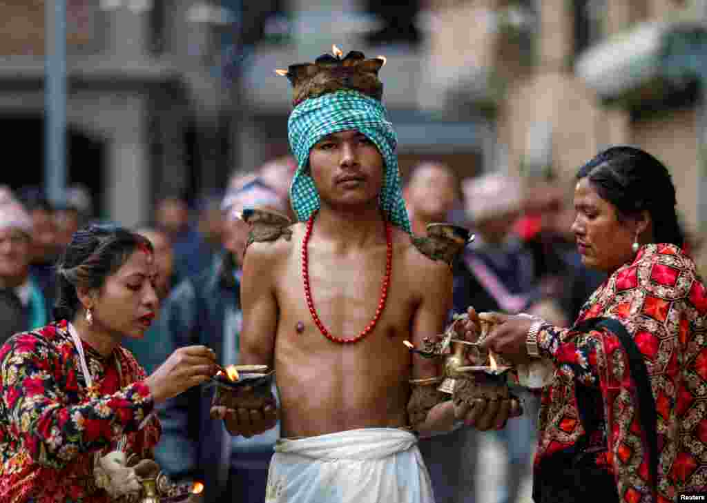 Devotees with lit oil lamps perform religious rituals during the Swasthani Brata Katha festival at Thecho in Lalitpur, Nepal.