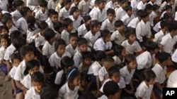 Cambodian school children sit under the shade of tree as they listen to teacher at Trapaing Loeuk primary school in Kampong Speu province.