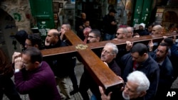 Feligreses cristianos portan un cruz mientras caminan por la Vía Dolorosa, en la Ciudad Vieja de Jerusalén, el vienres, 30 de marzo, de 2018, durante la celebración del Viernes Santo.