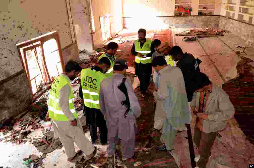 Pakistani investigators and security officials look for forensic evidence at a Shi'ite mosque in Shikarpur, Pakistan, Jan. 30, 2015.