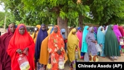 FILE - Women and villagers wait to receive food donations from the United Nations World Food Program in Damasak, northeastern Nigeria, Oct. 6, 2024.