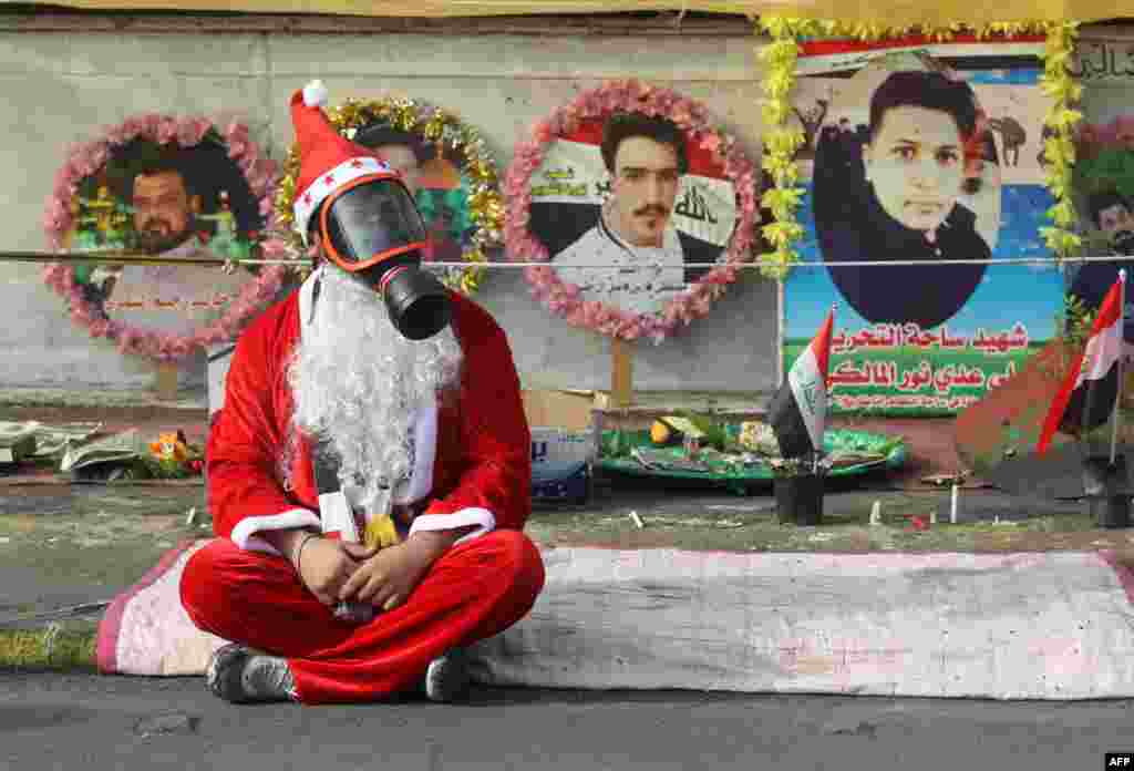 An Iraqi demonstrator wearing Santa Claus clothes and a gas mask sits on a blanket in the capital Baghdad&#39;s Tahrir Square, during ongoing anti-government protests.