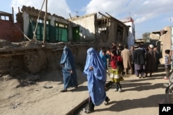 FILE - Afghan women walk towards a damaged house following an earthquake, in Kabul, Afghanistan, Monday, Oct. 26, 2015.