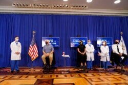 Wakil Presiden AS Mike Pence (duduk, paling kiri), istrinya Karen Pence (duduk di tengah), dan Ahli Bedah Umum AS Jerome Adams (duduk di sebelah kanan) bersiap untuk menerima suntikan vaksin COVID-19 Pfizer-BioNTech di Gedung Kantor Eksekutif Eisenhower, kompleks Gedung Putih, Washington, D.C., 18 Desember 2020.