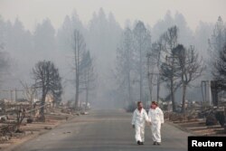 Las antropólogas forenses Kyra Stull (izq.) y Tatiana Viemincq caminan por un parque de casas rodantes destruido por el incendio Camp, en Paradise, California. Nov. 17 de 2018.