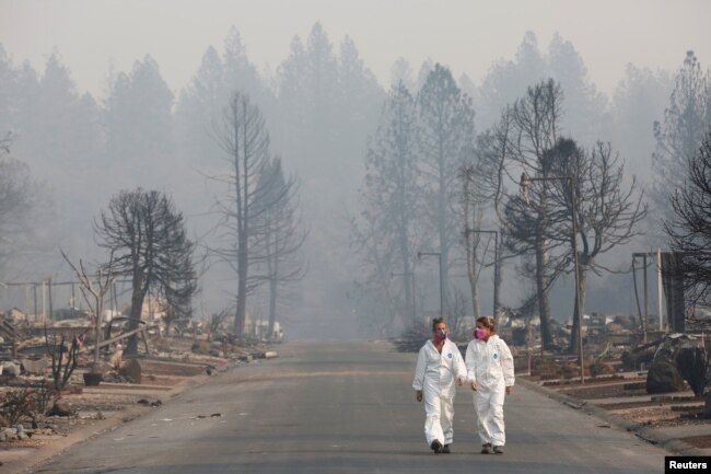 Las antropólogas forenses Kyra Stull (izq.) y Tatiana Viemincq caminan por un parque de casas rodantes destruido por el incendio Camp, en Paradise, California. Nov. 17 de 2018.