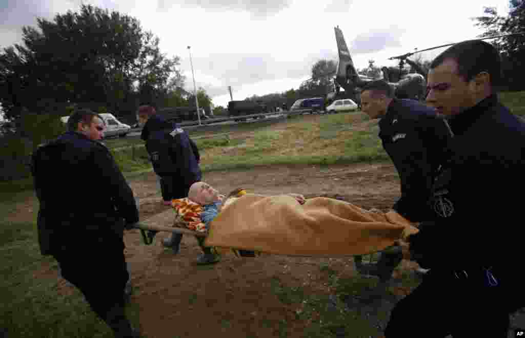 Police officers carry a man from a military helicopter during flood evacuation from Obrenovac, Serbia, May 17, 2014.