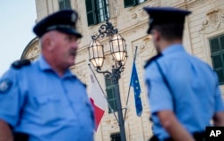 FILE - Police officers are seen on patrol patrol in Castile square, outside the office of the prime minister, in Valletta, Malta, Oct. 17, 2017.