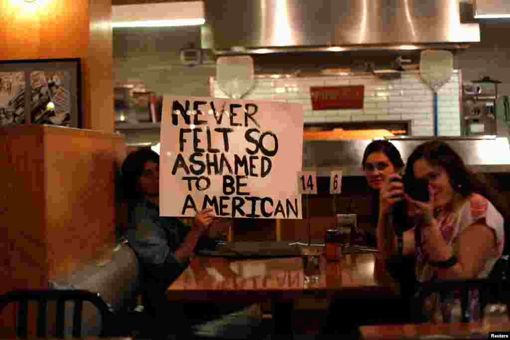 9일 미국 캘리포니아주 로스앤젤레스 중심가에서 트럼프 반대 시위가 열린 가운데, 식당 안에 있던 사람들도 시위대에 동조하는 문구가 적힌 종이를 들고 있다. '미국인인 것이 이렀게 부끄러웠던 적은 없다'고 적혀있다.